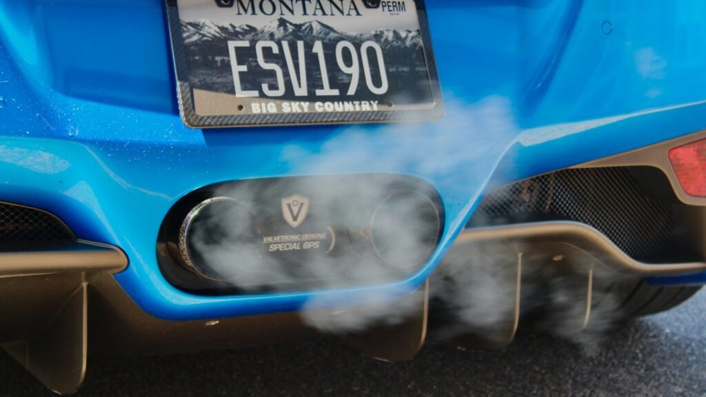 Fumée s'échappant des deux sorties d'échappement d'une voiture bleue