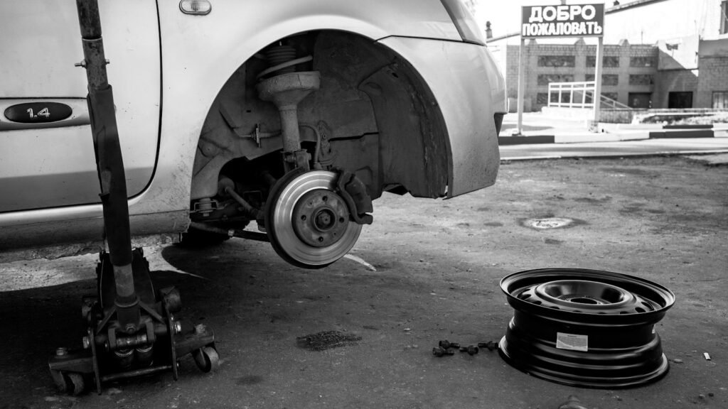 Voiture levée sur un cric avec la roue démontée en noir et blanc