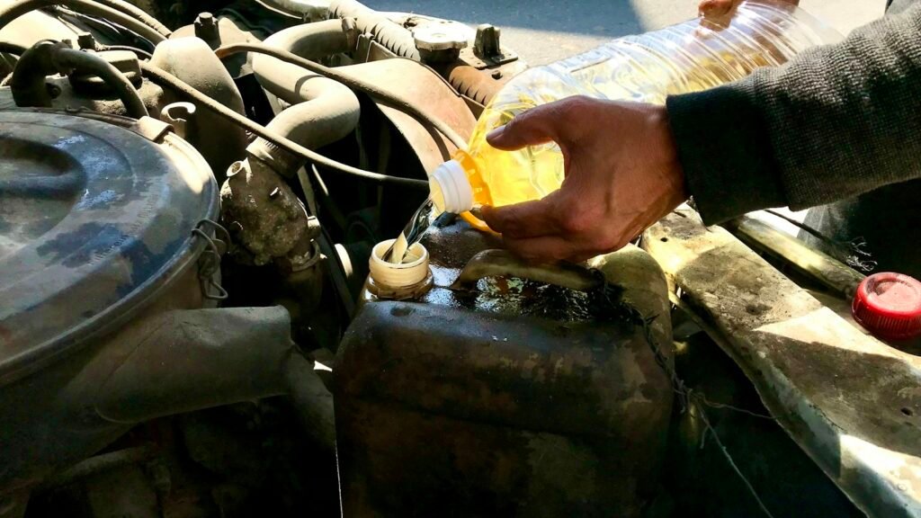 Homme versant un liquide dans le compartiment moteur d'une voiture